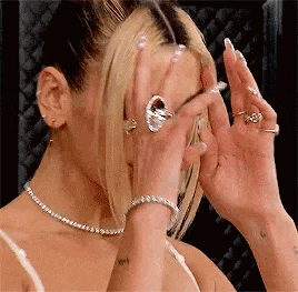 a woman with rings on her fingers is covering her face .