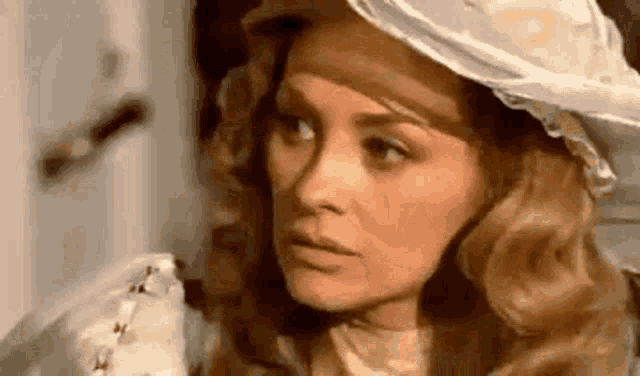 a close up of a woman wearing a white hat and looking at something .