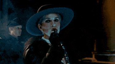 a woman in a hat is smoking a cigarette