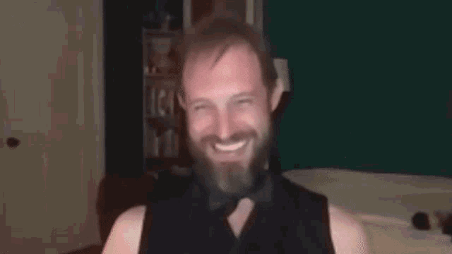 a man with a beard wearing a tuxedo and bow tie is making a funny face .
