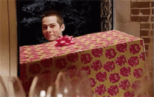 a man is peeking out from behind a box with a bow on it .