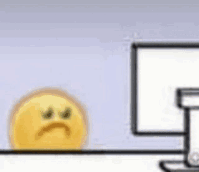 a cartoon smiley face is sitting on a desk next to a computer monitor .