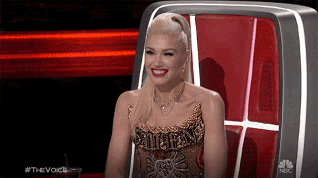 a woman is smiling while sitting in front of a nbc podium