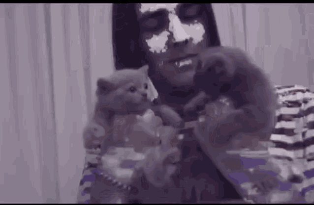 a man with a mask on his face is holding two kittens .