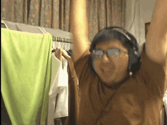 a man wearing headphones and sunglasses holds his arms up in the air
