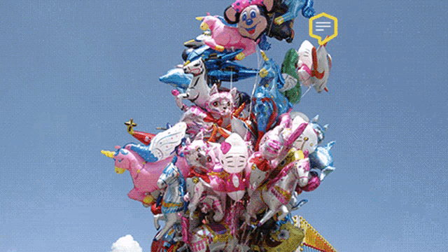 a bunch of balloons are stacked on top of each other including hello kitty and mickey mouse
