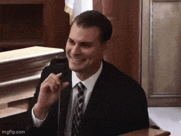 a man in a suit and tie is smiling in front of a microphone ..