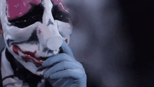 a close up of a person wearing a clown mask and gloves .