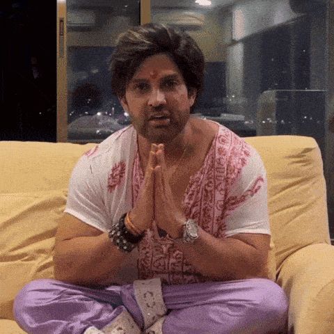 a man sits on a couch with his hands folded in front of his face