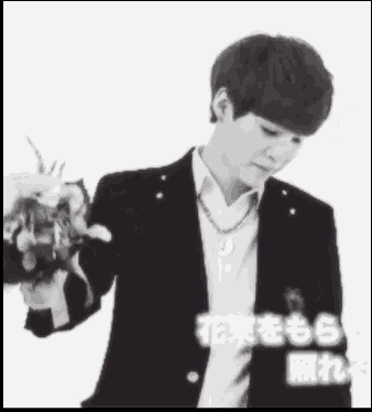 a man in a suit is holding a bouquet of flowers in his hand .