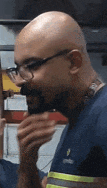 a bald man with glasses is talking on a phone .