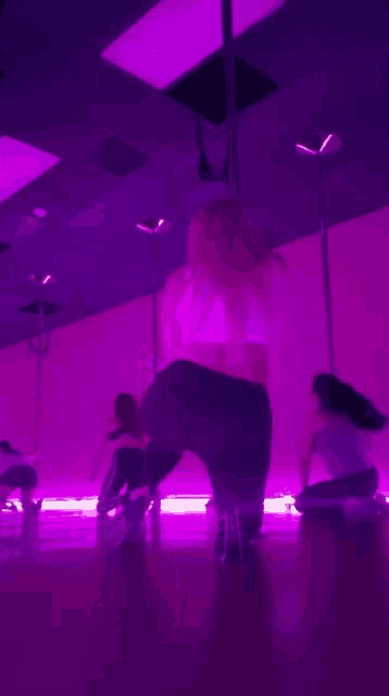 a woman is dancing in front of a mirror in a room with purple lights