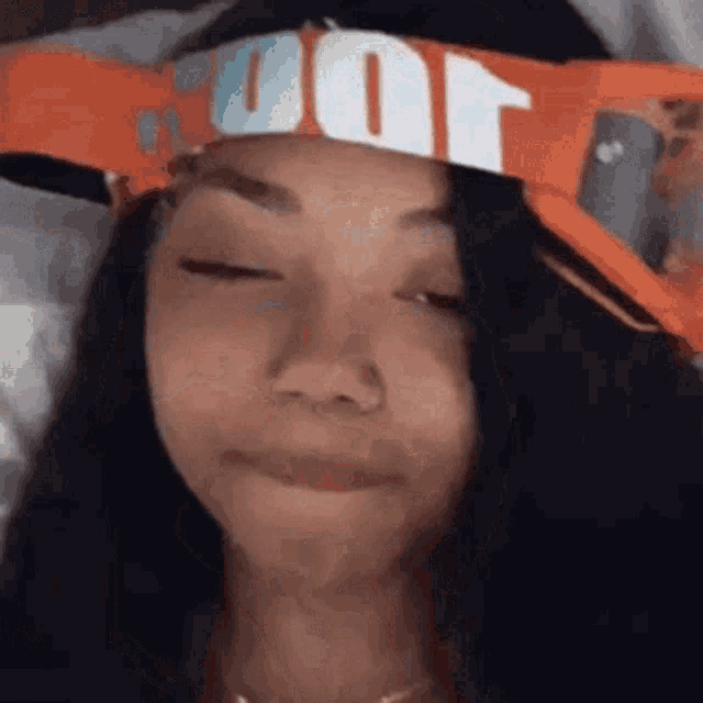 a girl is wearing a headband with the word nike on it and making a funny face .