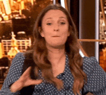 a woman in a blue polka dot shirt is making a funny face while talking on a television show .