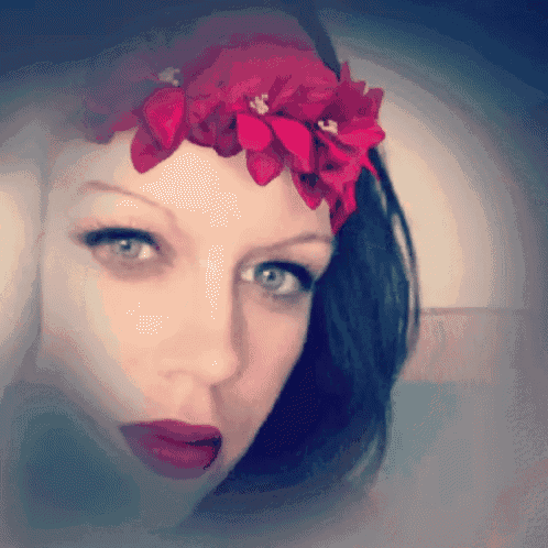 a close up of a woman 's face with a red flower crown on her head