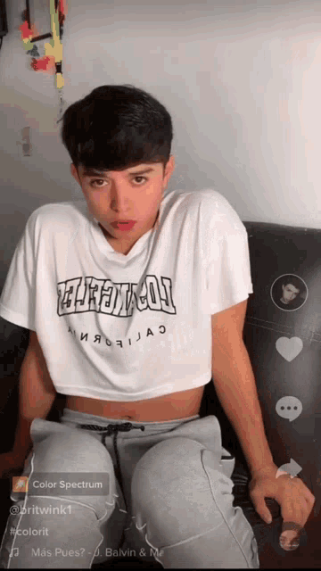 a young man wearing a white crop top with the word thrasher on it