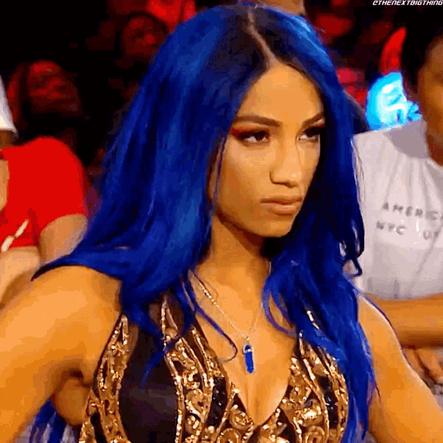 a woman with blue hair is wearing a necklace with a blue pendant .