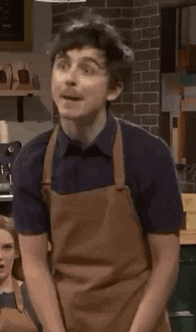 a man in a brown apron is dancing in a kitchen .