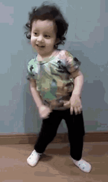 a little girl is dancing on the floor in a room .
