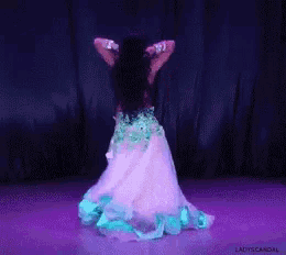 a woman in a white and blue dress is dancing in front of a purple curtain