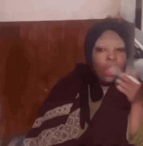 a woman wearing a scarf and a hijab is smoking a cigarette and blowing a bubble .
