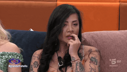 a woman sitting on a couch with the hashtag grandefratello on the bottom