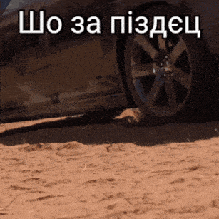 a black car is parked in the sand with the words " шо за пiздец " written above it