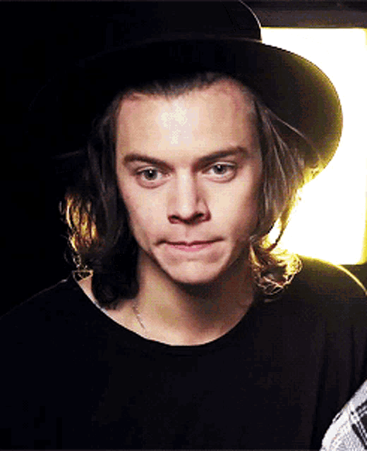 a young man with long hair wearing a black hat and a black shirt