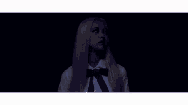 a woman in a blue skirt and white shirt is walking in a dark room