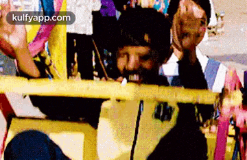 a man with a beard is sitting in a yellow vehicle with a group of people behind him .