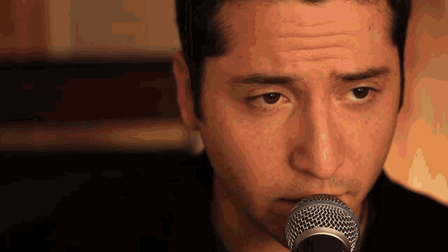 a close up of a man 's face with a microphone in front of him