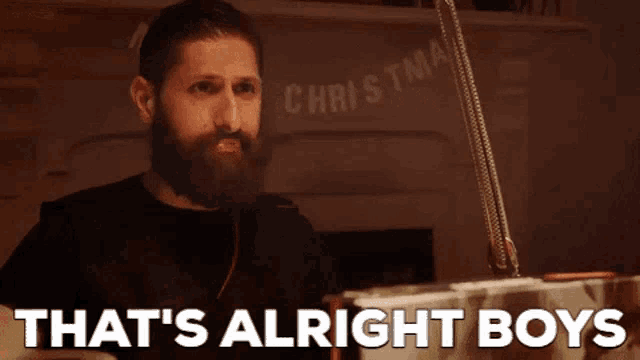 a man with a beard is saying that 's alright boys in front of a christmas sign