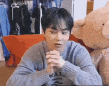 a young man is sitting in front of a teddy bear .