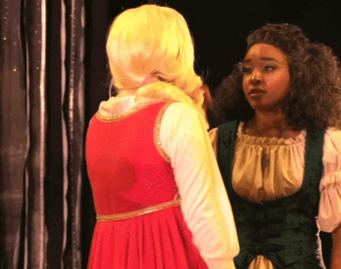 a woman in a red dress talks to another woman
