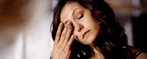 a woman is covering her face with her hand .