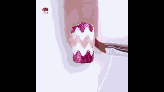 a person is painting their nails with a pink and white chevron pattern .
