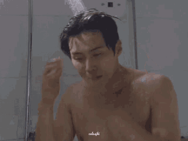 a shirtless man is taking a shower and washing his hair