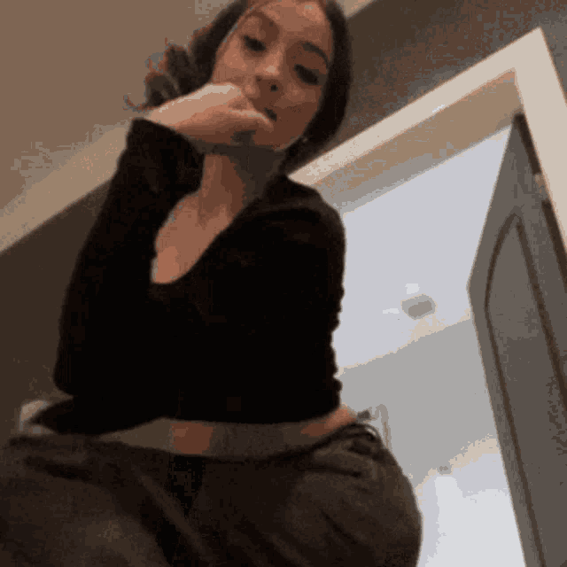 a woman in a black shirt and black pants is standing in a doorway