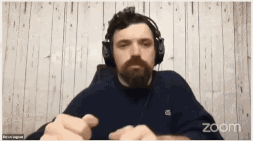 a man wearing headphones is on a zoom call with a wooden background