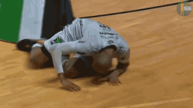 a basketball player is kneeling on the floor in front of a sign that says nbb