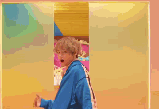 a man wearing a blue jacket and a red tie is standing in front of a colorful wall .