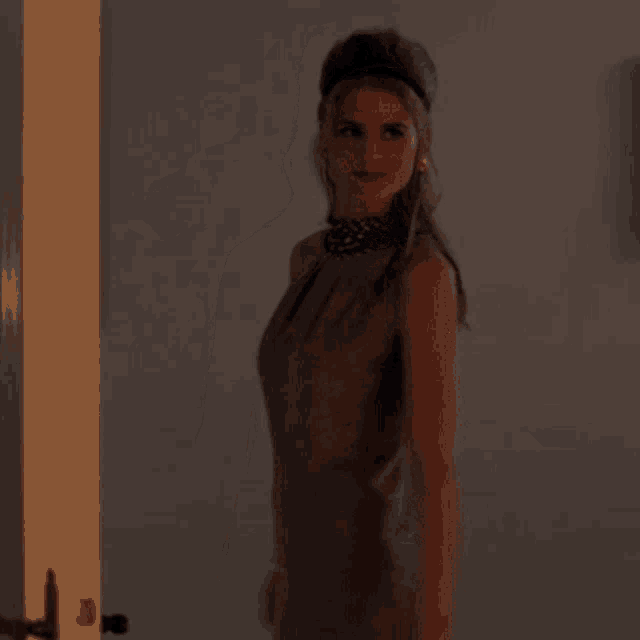 a woman in a dress is standing in front of a door and looking at the camera .