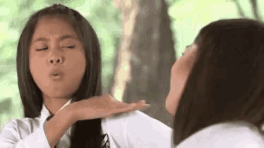 a girl is blowing a kiss to another girl while looking at herself in the mirror .
