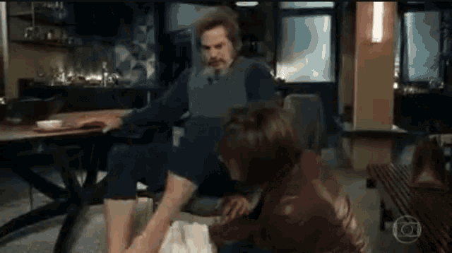 a man and a woman are sitting at a table and the woman is touching the man 's leg .