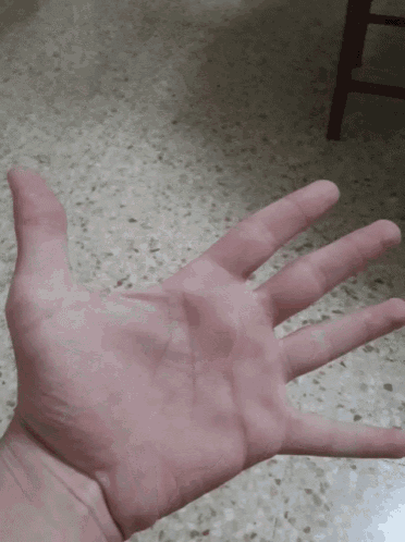 a person 's hand is spread out on a tiled floor