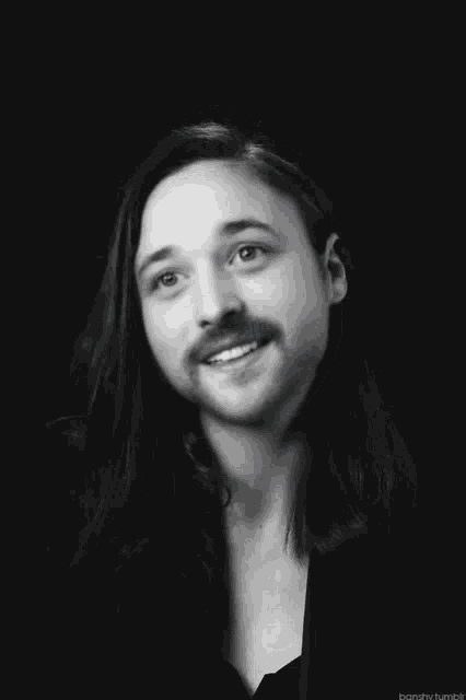 a black and white photo of a man with long hair
