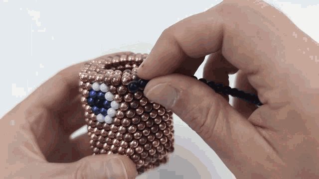 a person is holding a bracelet made of beads with a blue white and black design