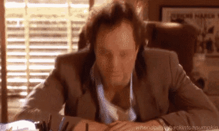 a man in a suit and tie is sitting at a desk in front of a window in an office .