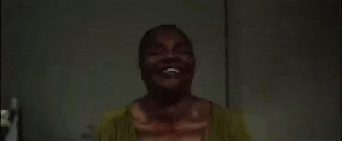 a woman with blood on her face is standing in a dark room with her eyes closed .
