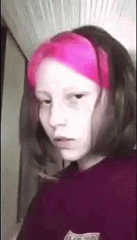 a girl with pink hair is wearing a headband and making a funny face .